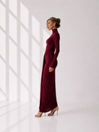 Woman wearing a burgundy dress with long sleeves and a high neckline.