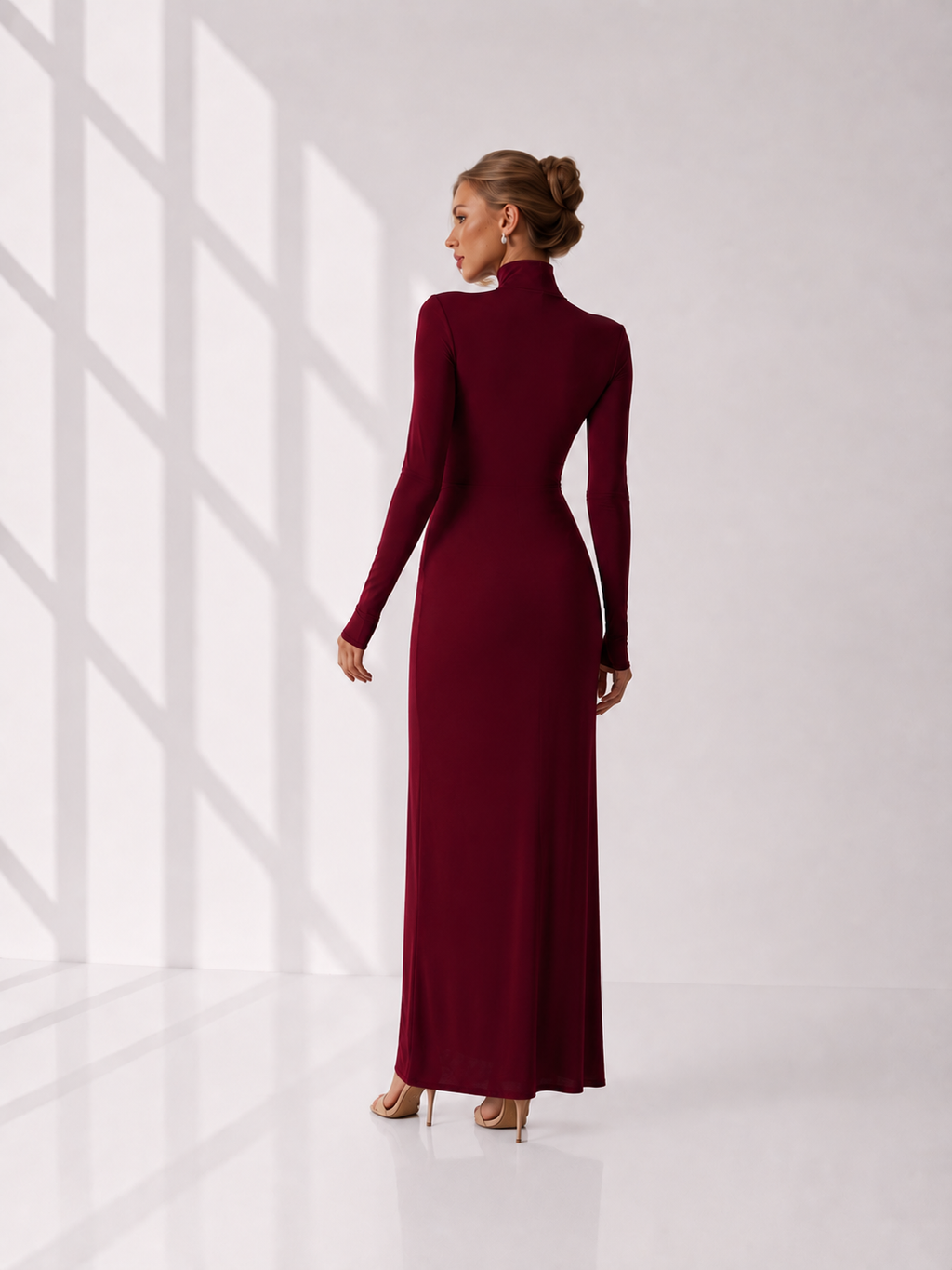 Woman wearing a burgundy long-sleeve dress against a white background