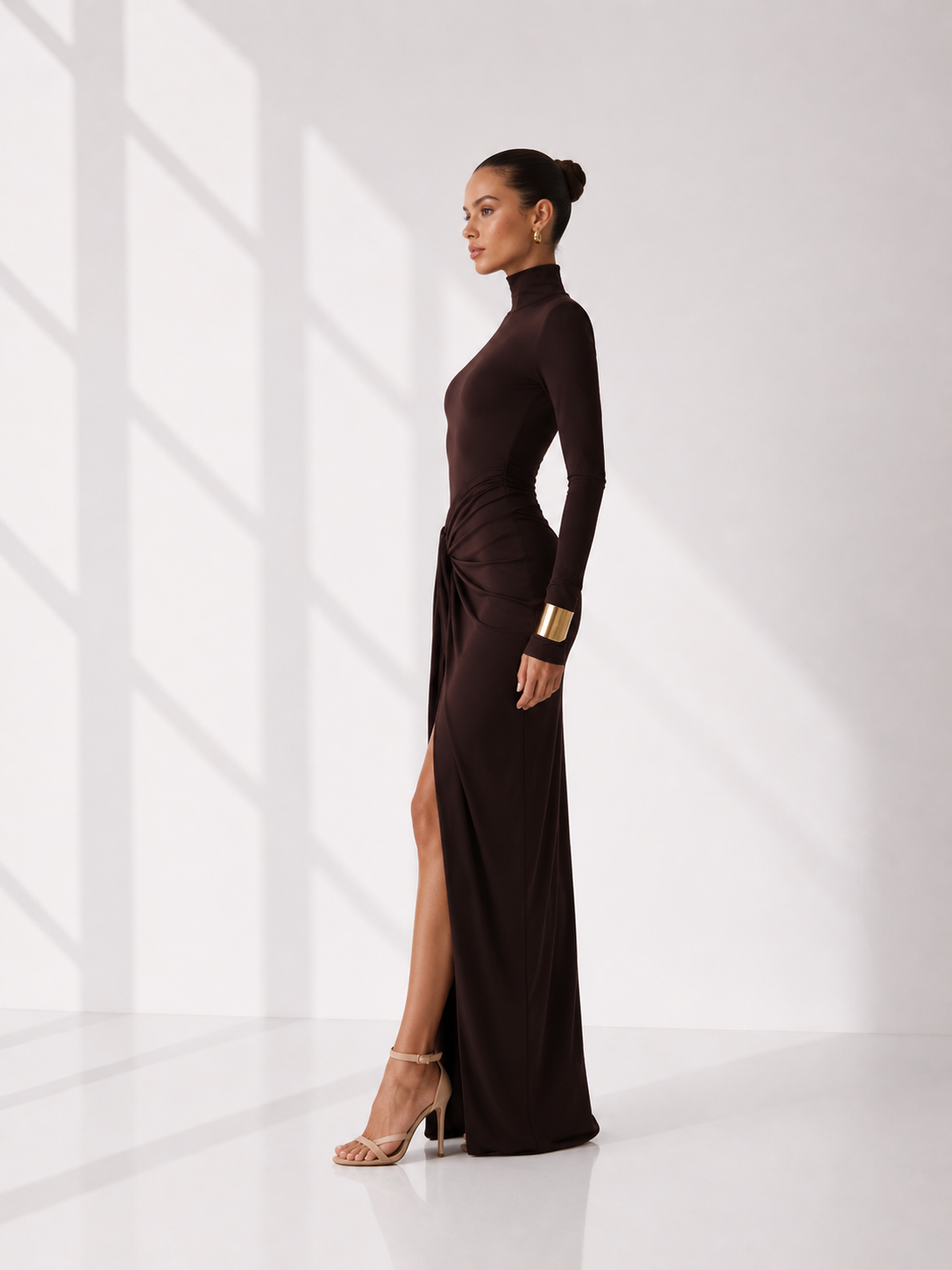 Woman wearing a brown dress with a high slit in a minimalistic setting