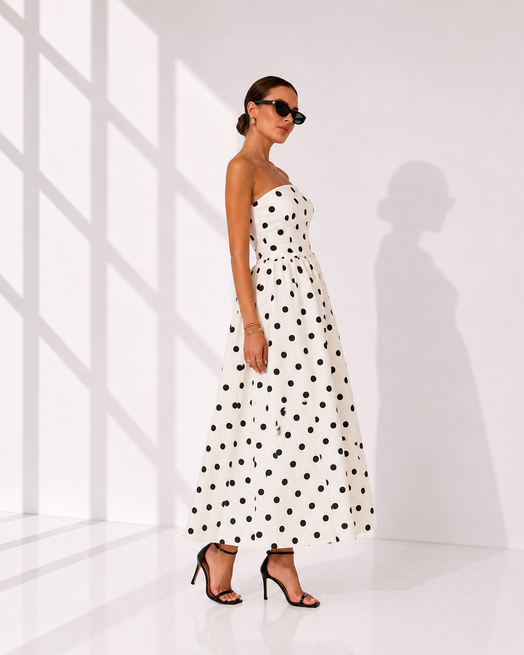 Woman wearing a strapless polka dot dress in a minimal white room