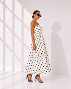 Woman wearing a strapless polka dot dress in a minimal white room