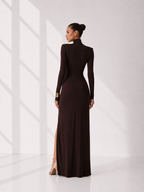 Woman wearing a long, dark brown dress with a high slit on a white background