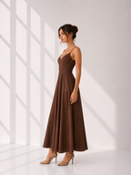 Woman wearing a brown dress standing in a bright room with white walls.