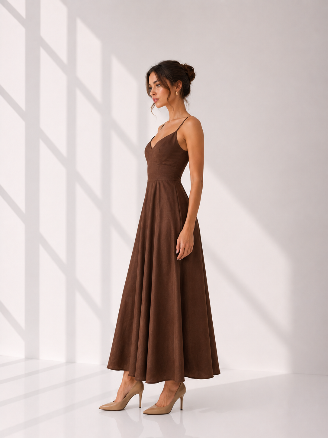 Woman wearing a brown dress standing in a bright room with white walls.