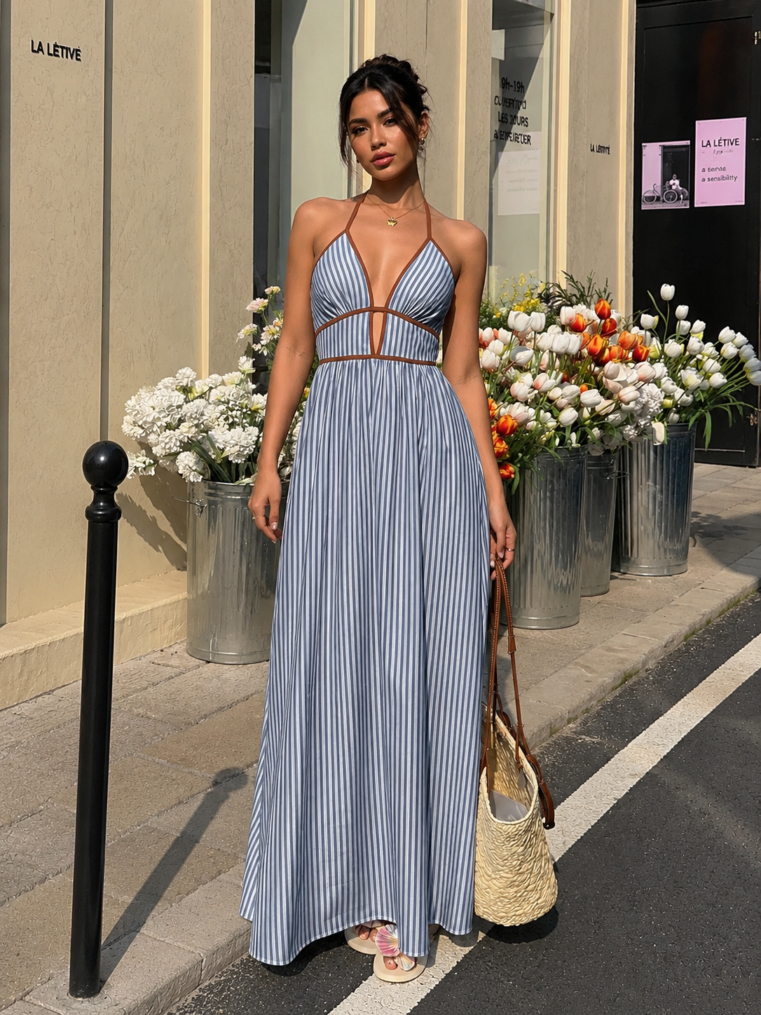 Woman in a blue striped dress standing on a street with flower arrangements in the background