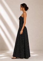 Woman wearing a black polka dot dress against a neutral background