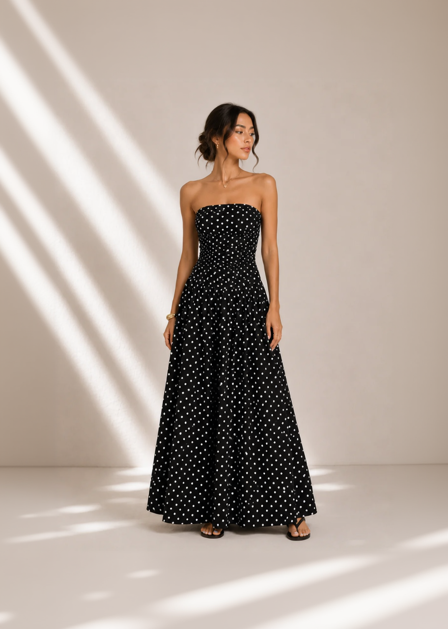 Woman wearing a black strapless dress with white polka dots against a neutral background