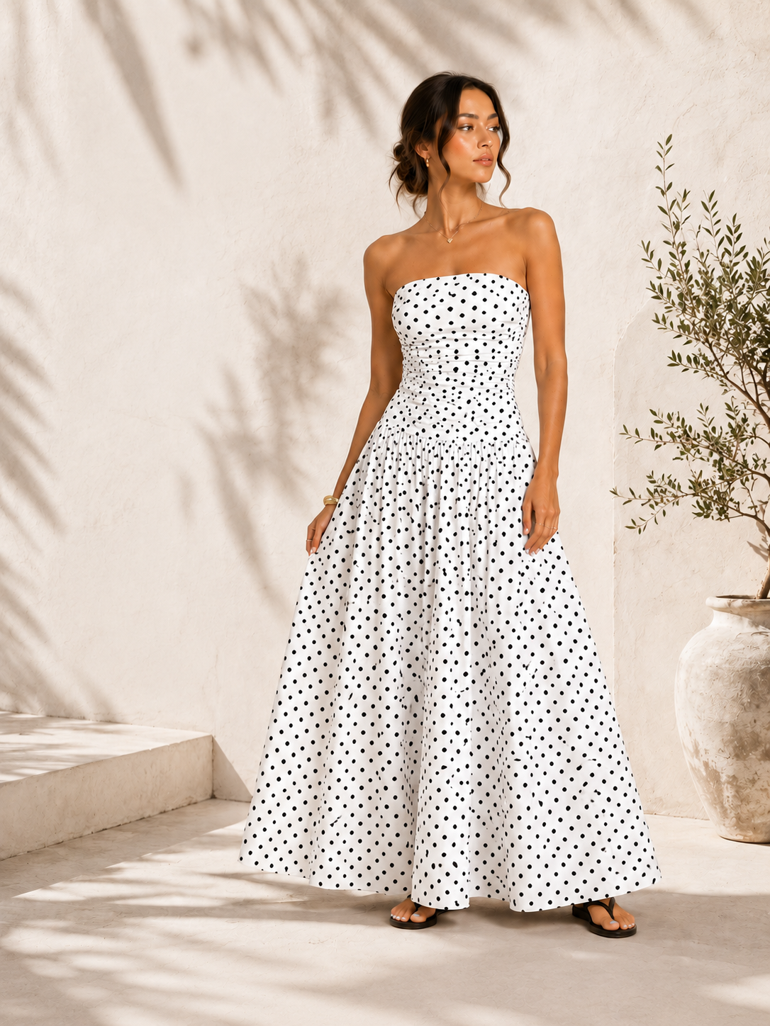 Woman wearing a strapless polka dot dress against a neutral background
