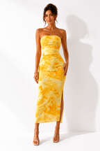 Woman wearing a yellow tie-dye strapless dress on a white background