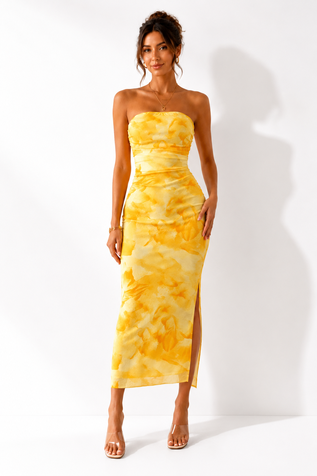 Woman wearing a yellow tie-dye strapless dress on a white background