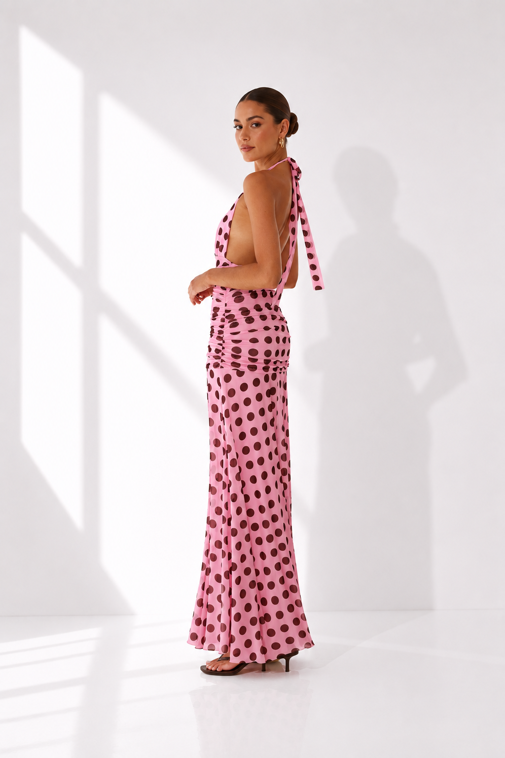 Woman wearing a pink polka dot dress with a white background