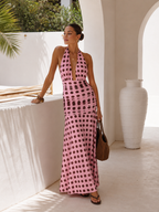Woman in a pink polka dot dress standing in a sunlit outdoor setting.