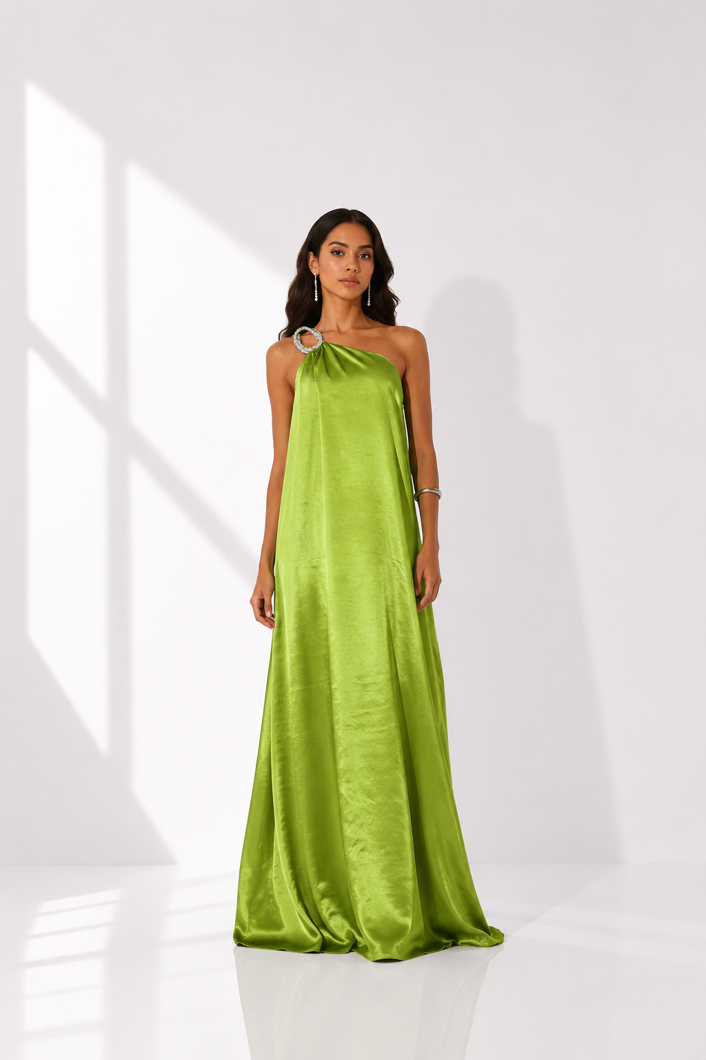 Woman wearing a green one-shoulder dress in a bright room
