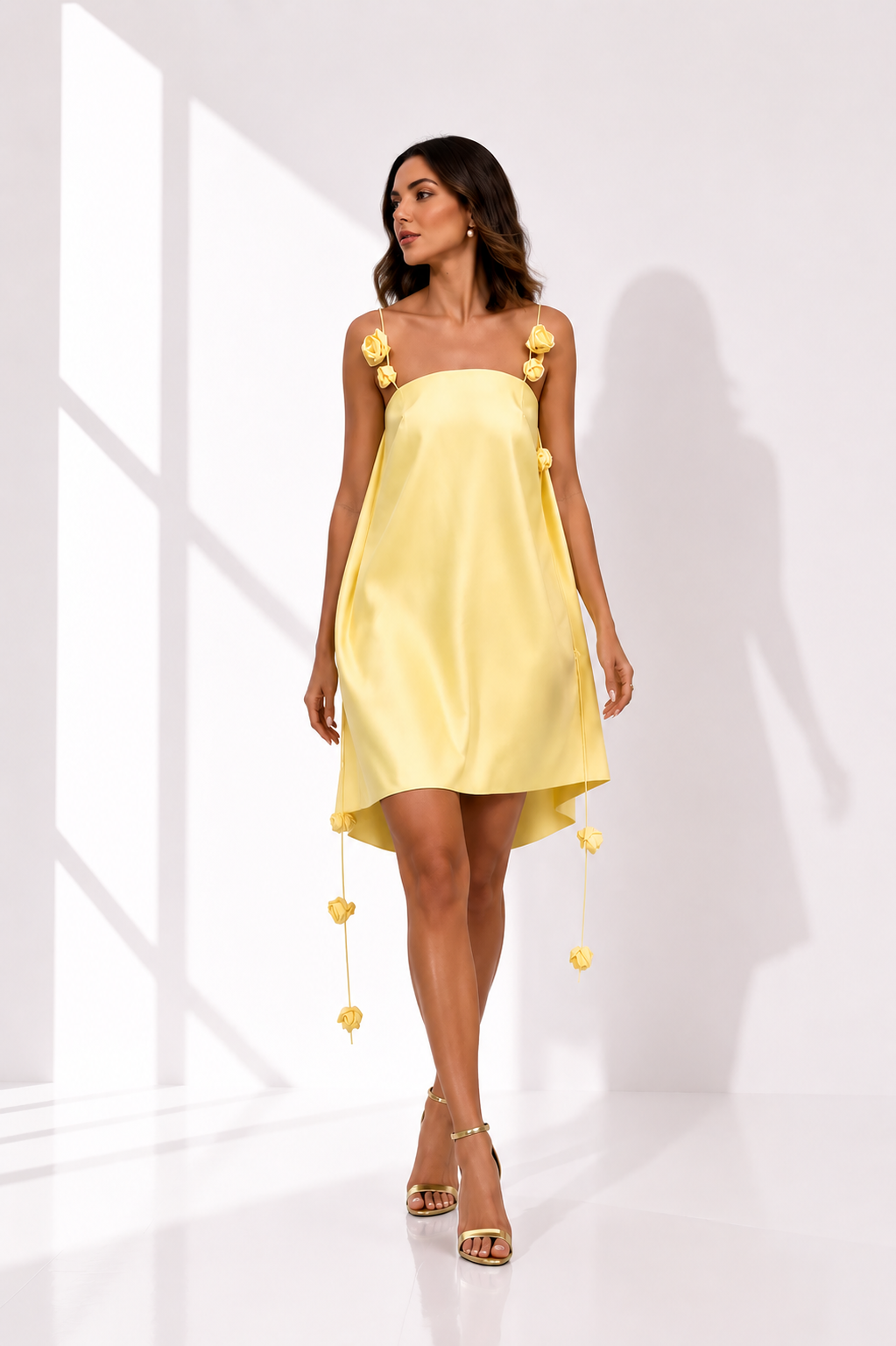Woman wearing a yellow dress with floral details on a white background