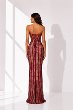 Woman wearing a burgundy strapless gown with lace detailing in a bright room.