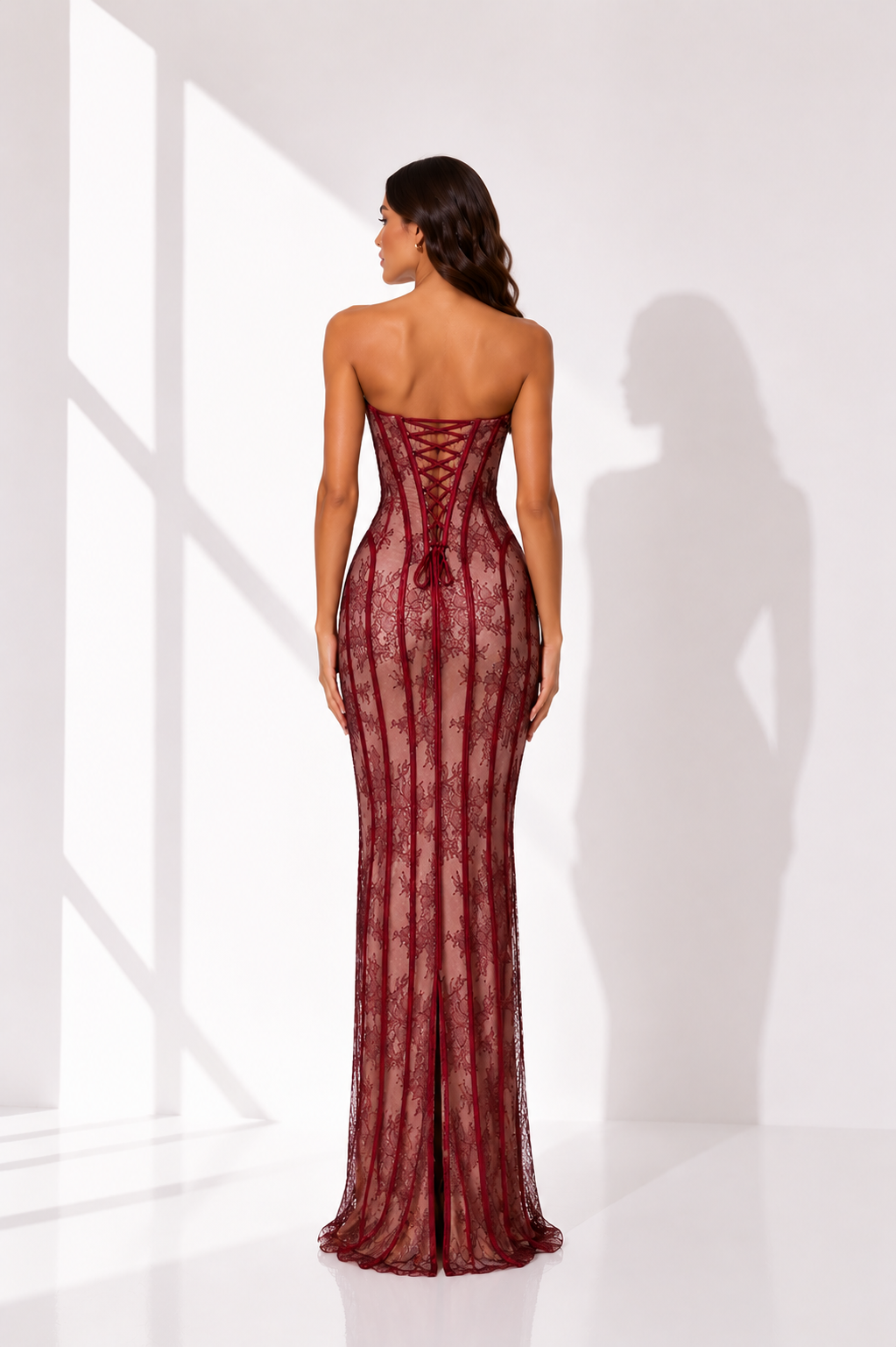 Woman wearing a burgundy strapless gown with lace detailing in a bright room.