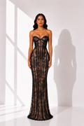 Woman wearing a black lace evening gown against a white background