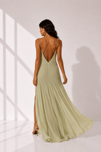Woman wearing a light green evening gown with a slit on a white background