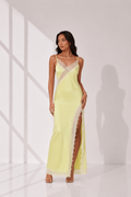 Woman wearing a light yellow evening gown with lace details on a white background