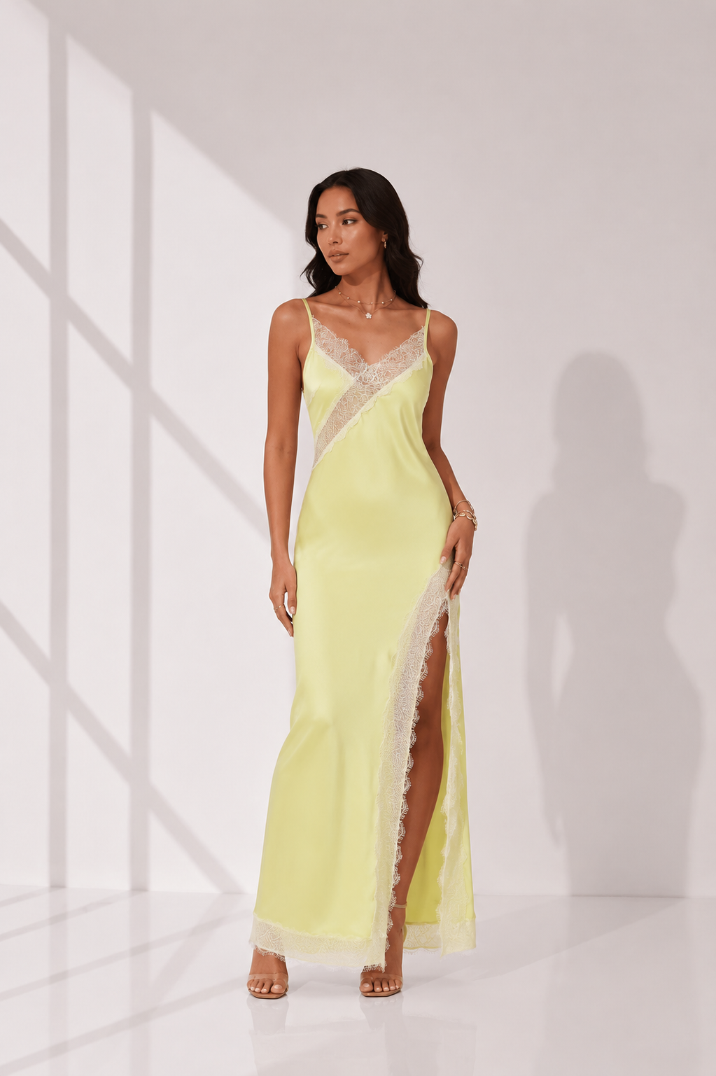 Woman wearing a light yellow evening gown with lace details on a white background