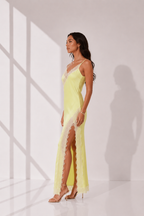 Woman wearing a yellow slip dress with lace details in a minimalistic setting