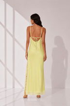 Woman wearing a light green dress with thin straps in a minimalistic setting