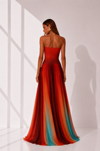 Woman wearing a strapless, multicolored evening gown in a minimalistic setting.