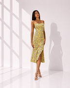 Woman wearing a yellow floral dress in a bright, minimalistic setting