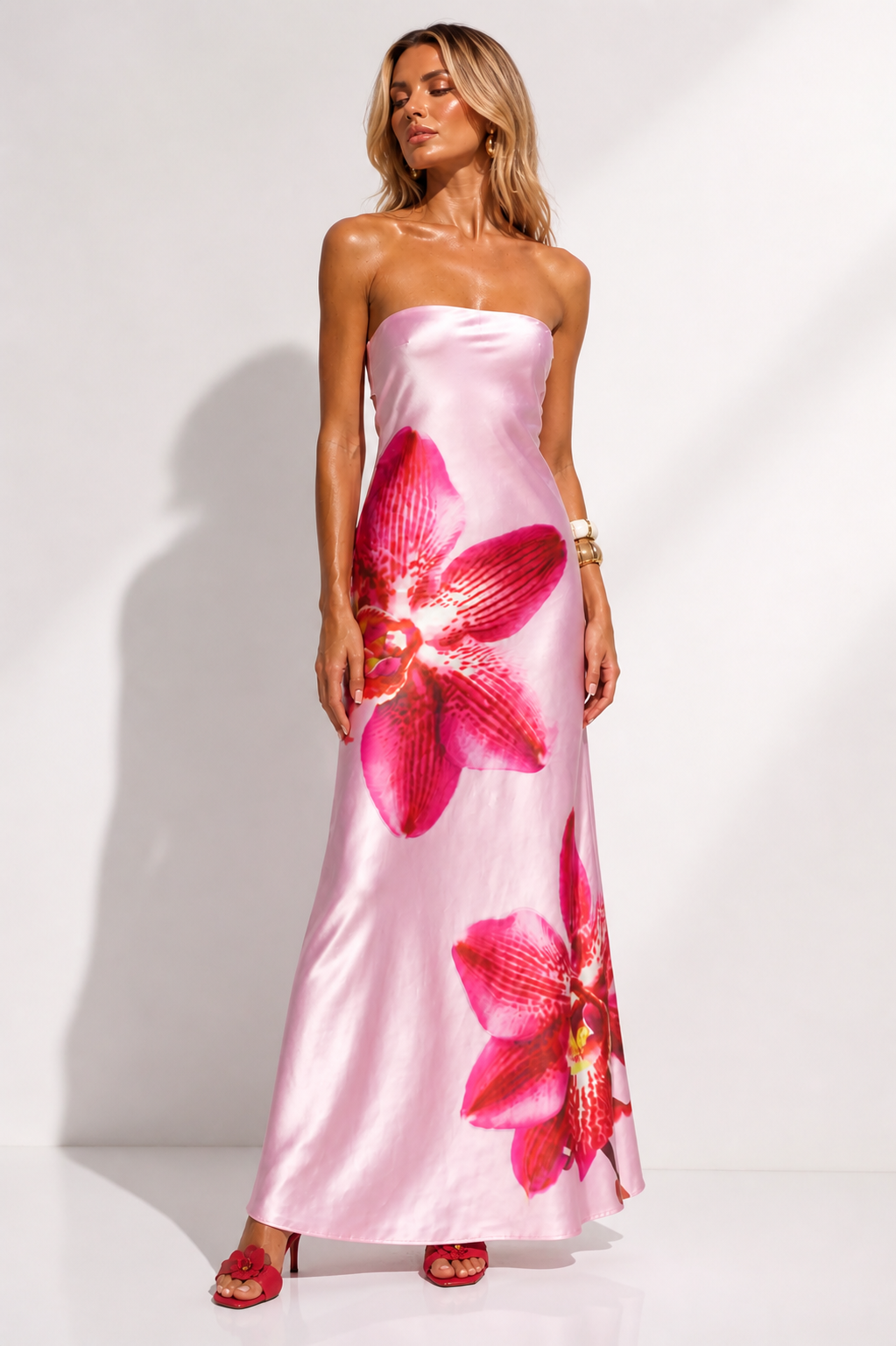 Woman wearing a pink strapless dress with floral patterns on a white background