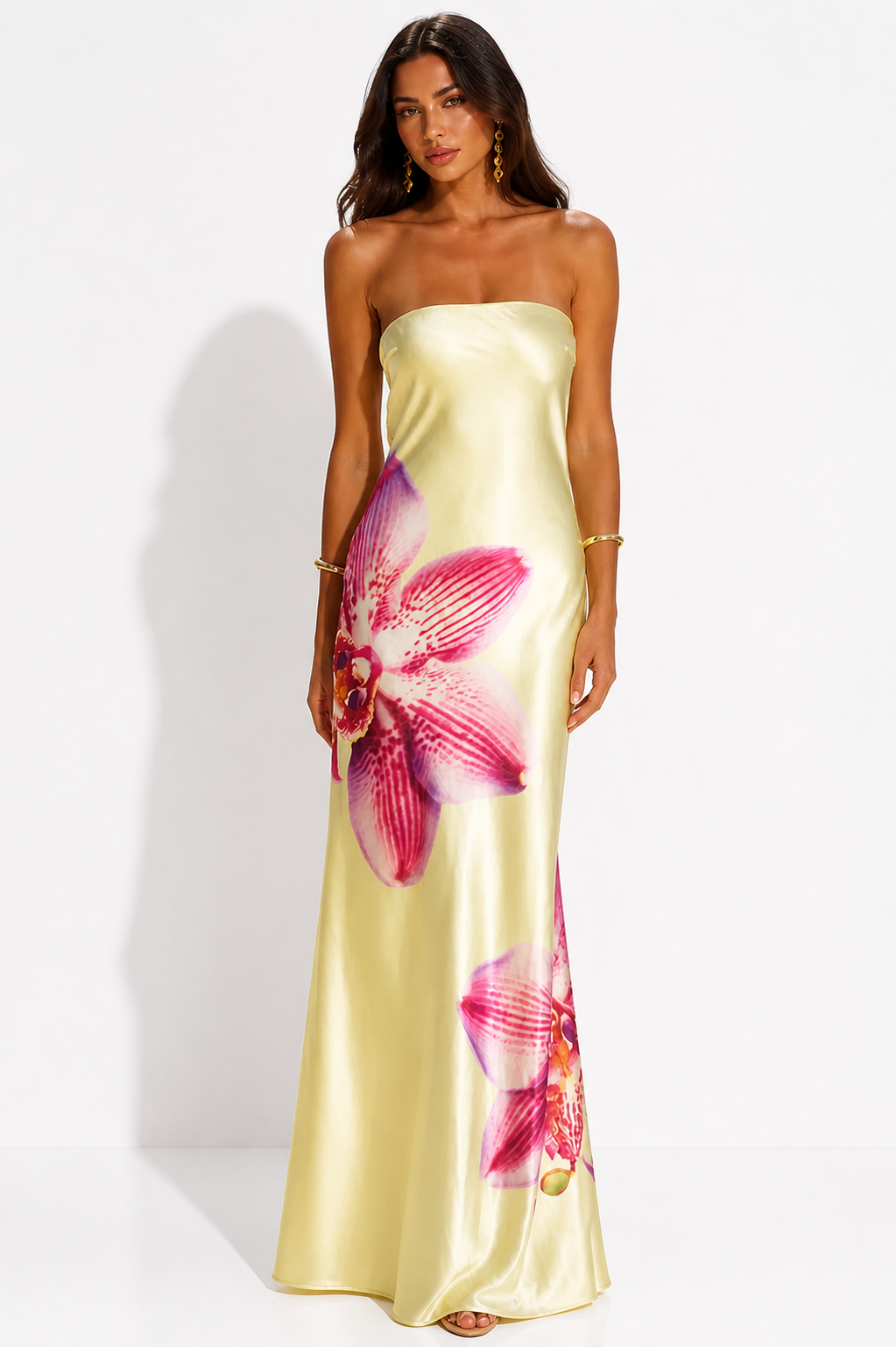 Woman wearing a strapless yellow dress with pink floral patterns on a white background