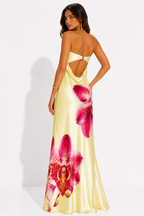 Woman wearing a yellow dress with pink floral designs on a white background