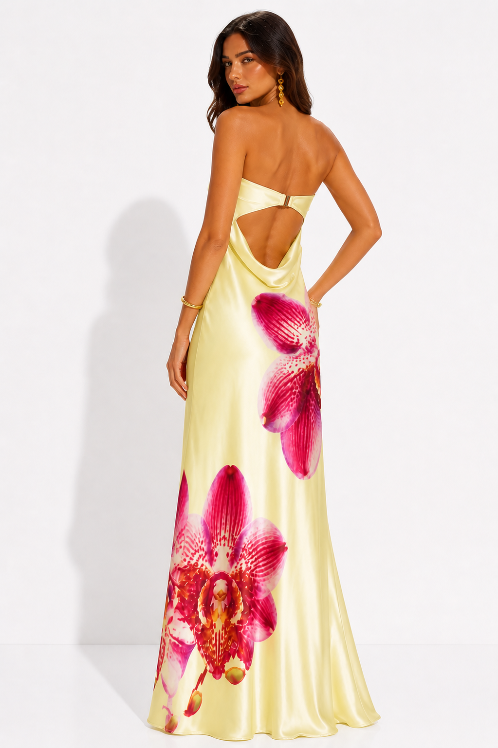 Woman wearing a yellow dress with pink floral designs on a white background