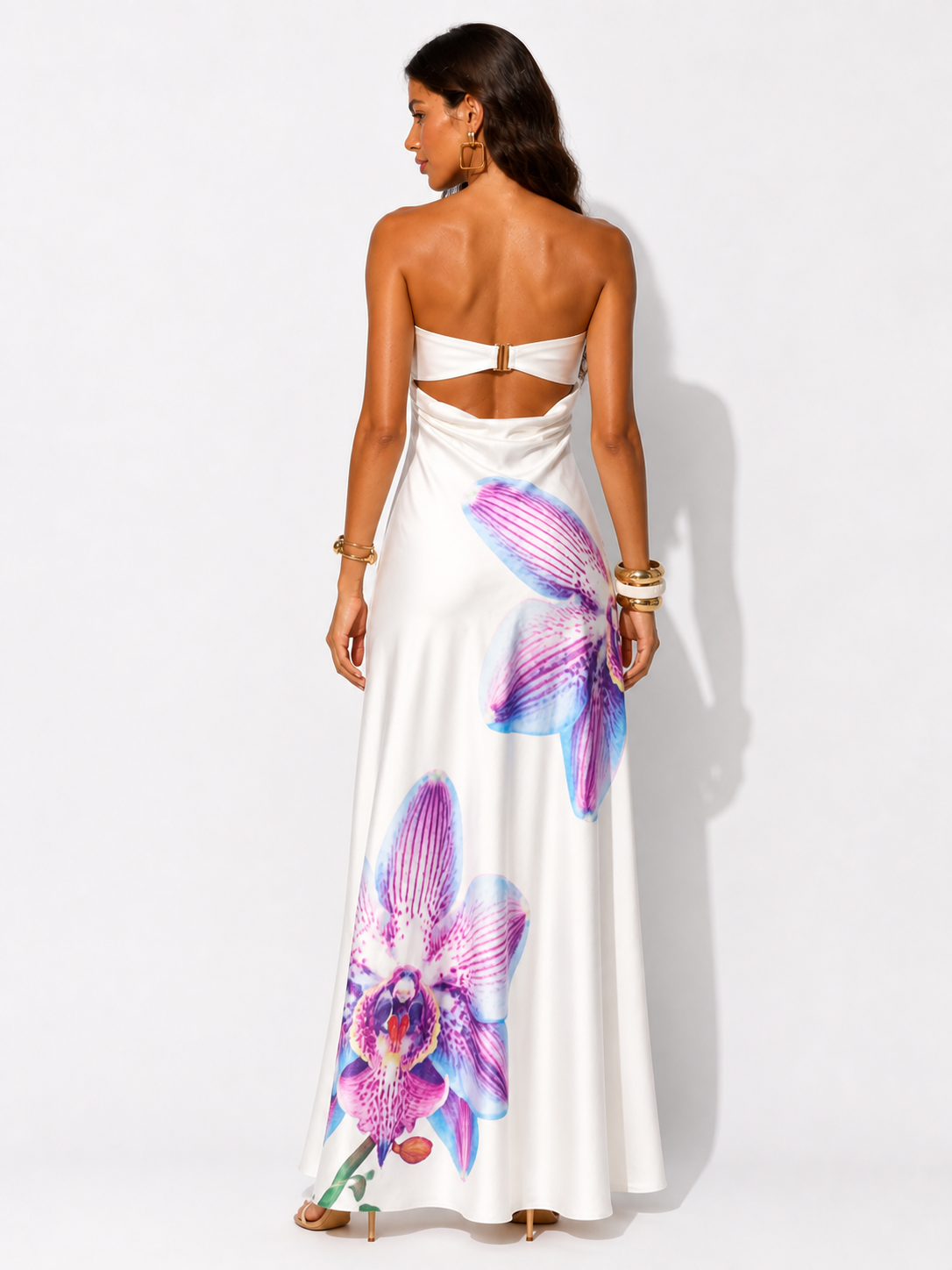 Woman wearing a white strapless dress with colorful floral patterns on a white background