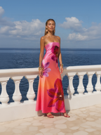 Woman in a strapless floral dress standing on a balcony with ocean view
