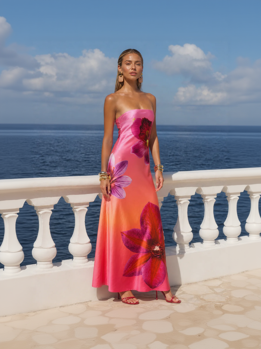 Woman in a strapless floral dress standing on a balcony with ocean view