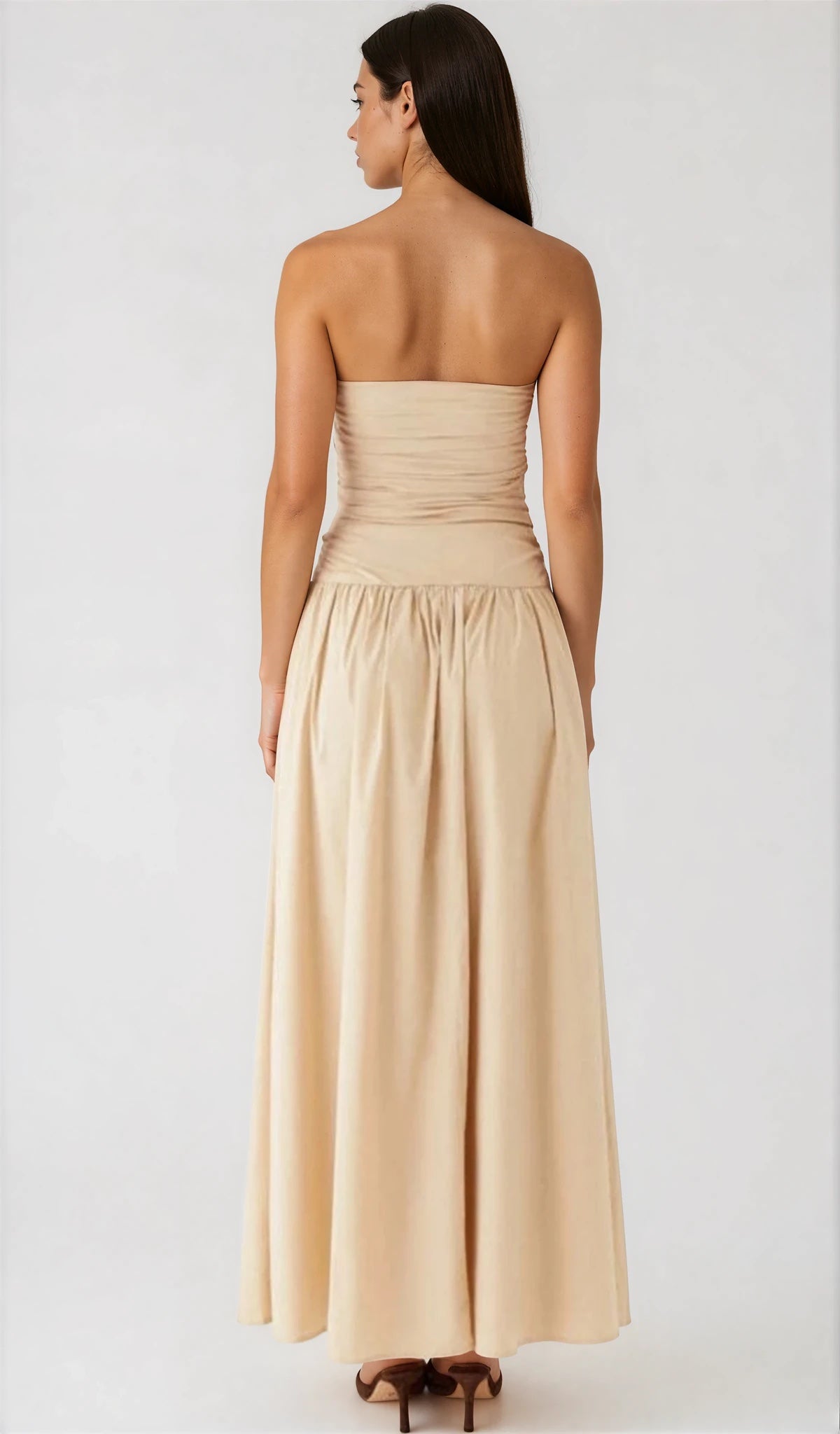 Woman wearing a beige strapless gown on a white background