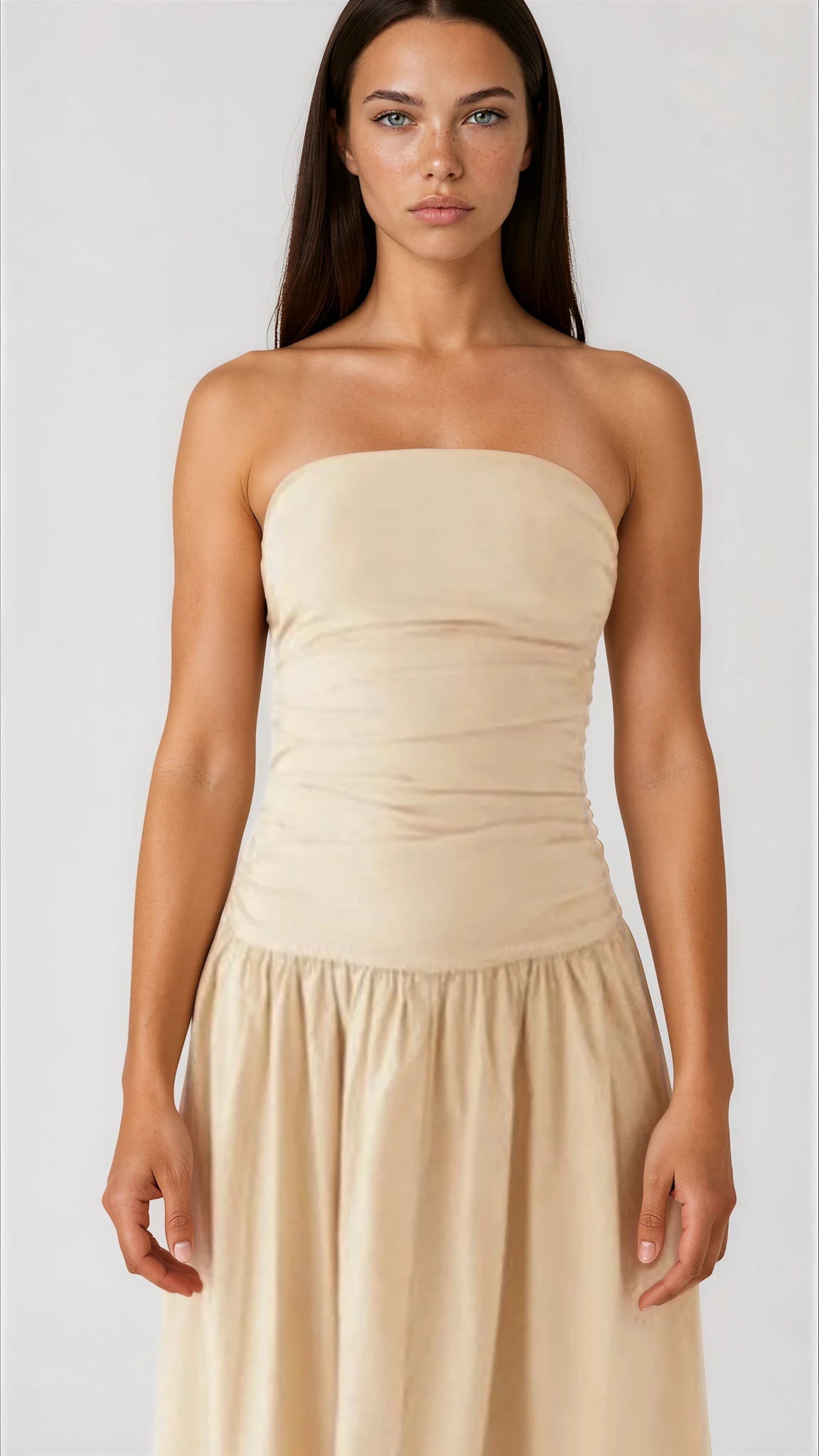 Woman wearing a beige strapless dress against a white background