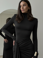 Woman wearing a black dress with long sleeves in a neutral setting