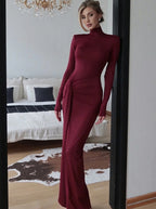 Woman in a burgundy dress standing in a room with a couch and cowhide rug.