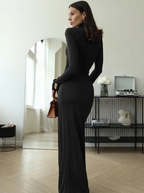 Woman in a black dress standing in a room with a mirror and decor.
