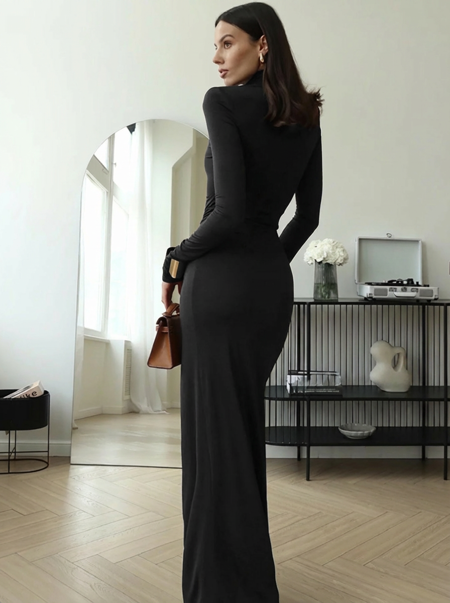 Woman in a black dress standing in a room with a mirror and decor.