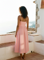 Woman in a pink dress standing on a stone staircase with a scenic view.