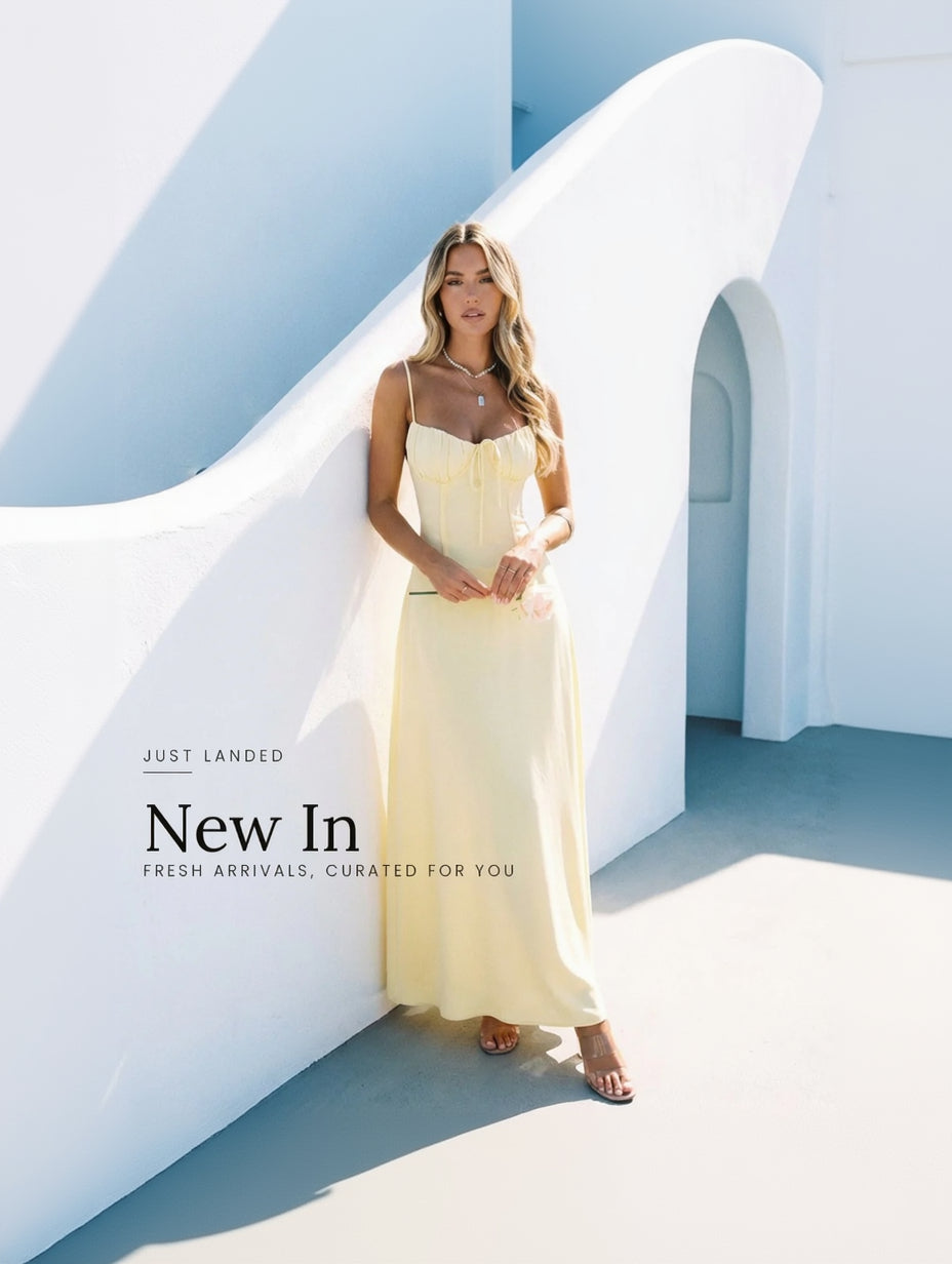Woman in a yellow dress standing in a sunlit, architectural setting with 'New In' text overlay.
