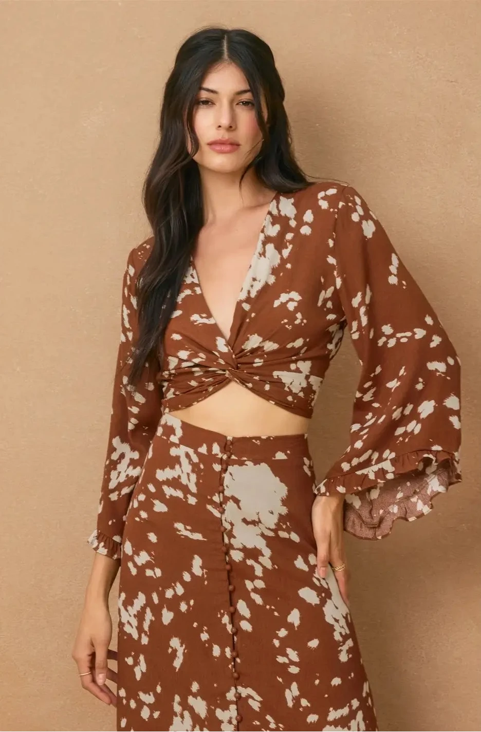 Woman wearing a brown and beige patterned outfit against a beige background