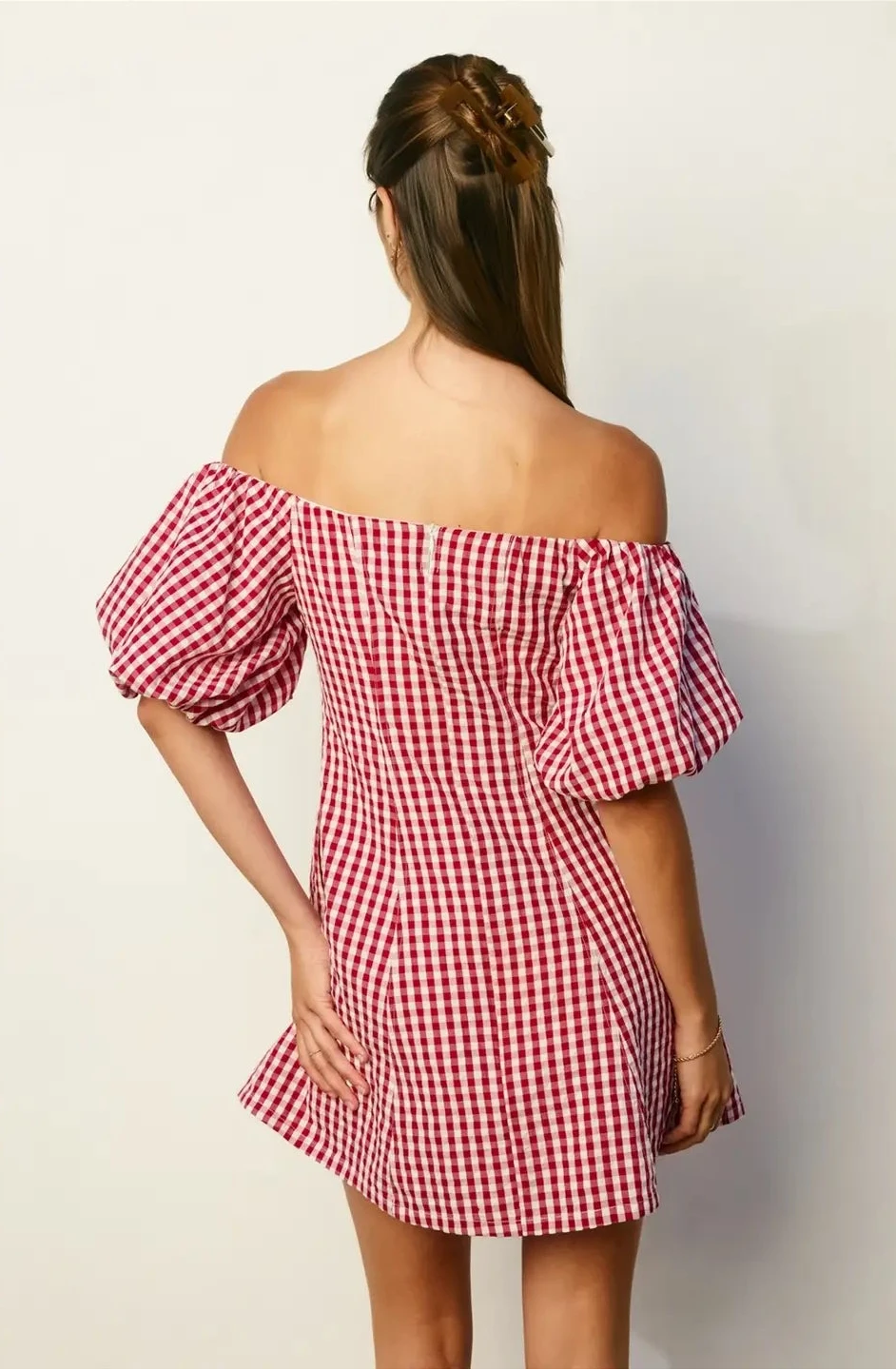 Red and white checkered off-shoulder dress worn by a model against a plain background